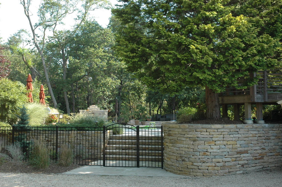 Idee per un giardino chic esposto a mezz'ombra dietro casa in estate con pavimentazioni in pietra naturale e recinzione in metallo