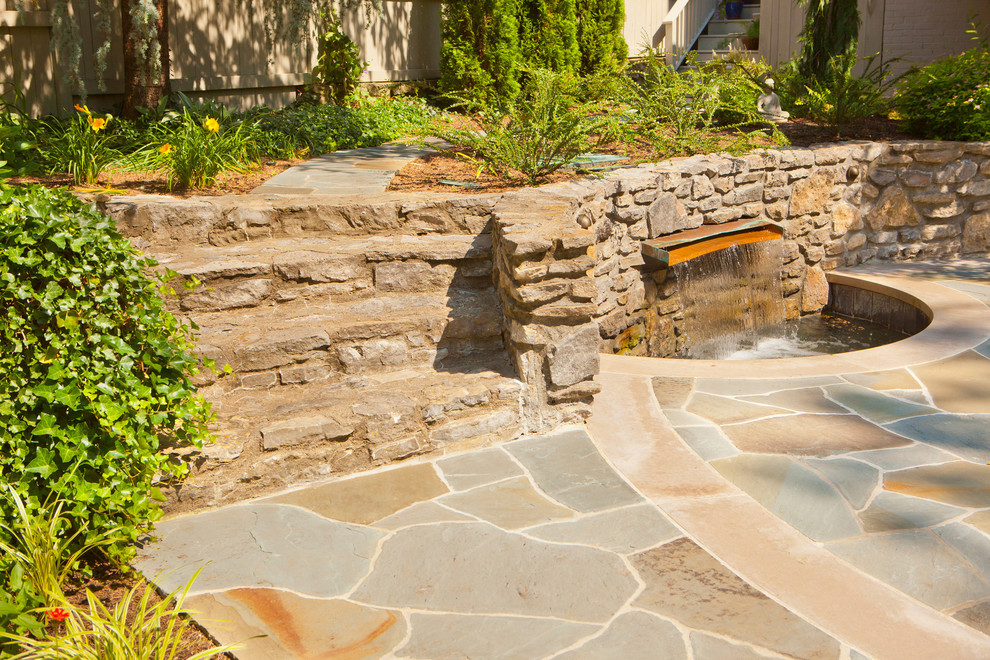Esempio di un ampio giardino stile rurale esposto a mezz'ombra dietro casa in estate con un muro di contenimento e pavimentazioni in pietra naturale