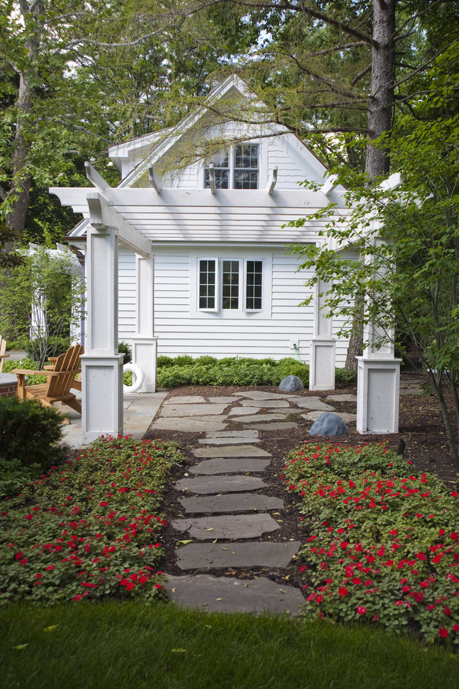 Ejemplo de jardín clásico en patio trasero con adoquines de piedra natural y pérgola