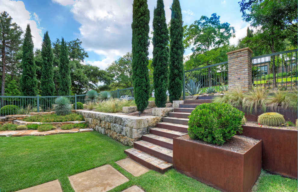 Ispirazione per un grande giardino formale minimalista esposto in pieno sole davanti casa in primavera con un muro di contenimento e pavimentazioni in pietra naturale