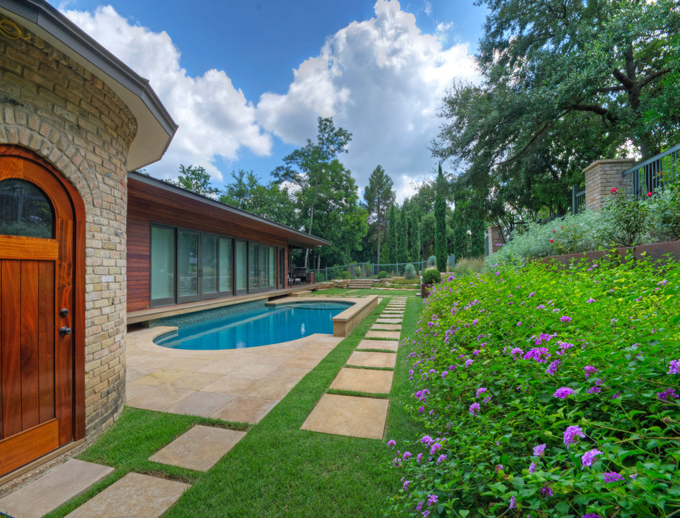 Esempio di un grande giardino xeriscape minimalista esposto in pieno sole davanti casa in primavera con un muro di contenimento e pavimentazioni in pietra naturale