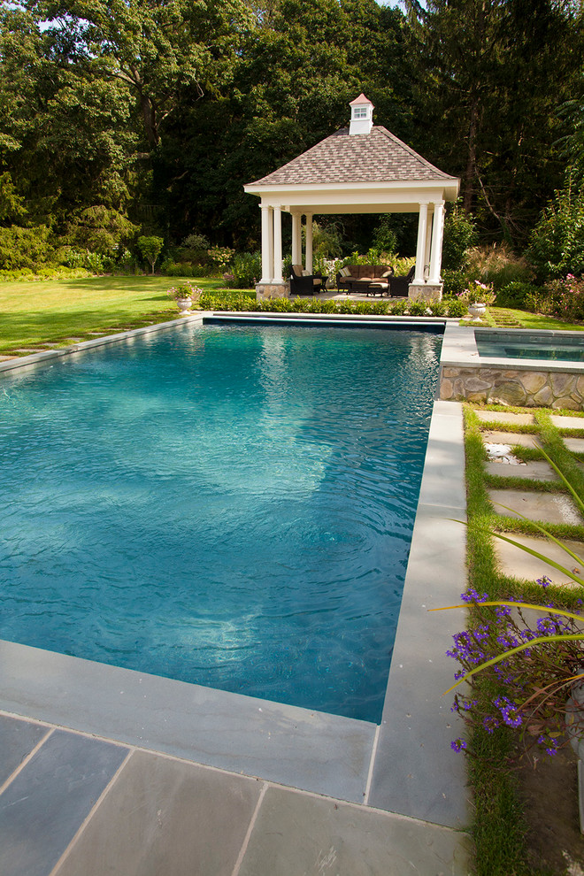 Mittelgroßer Klassischer Pool hinter dem Haus mit Wasserspiel und Natursteinplatten in New York