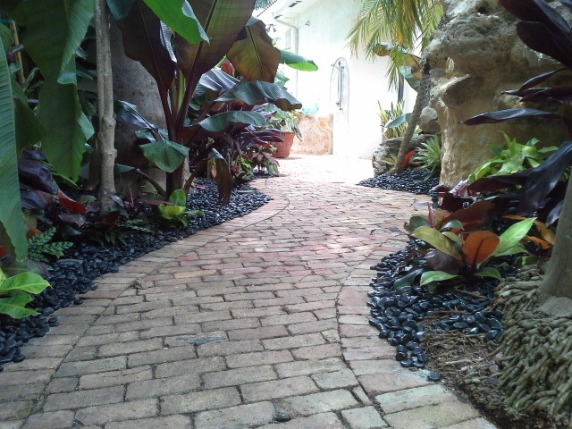 Idee per un grande giardino tropicale esposto a mezz'ombra in cortile con fontane e ghiaia