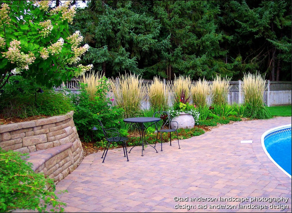 Photo of a traditional full sun backyard concrete paver retaining wall landscape in Minneapolis for summer.