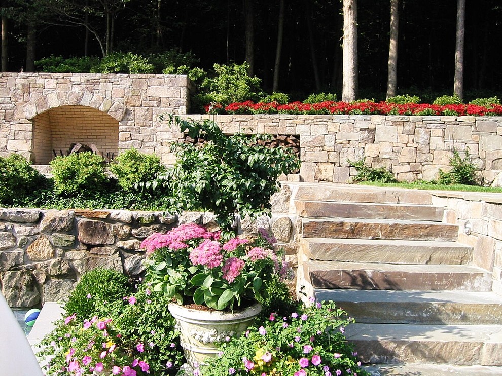 Immagine di un grande giardino formale chic esposto in pieno sole dietro casa in primavera con un muro di contenimento e pavimentazioni in pietra naturale