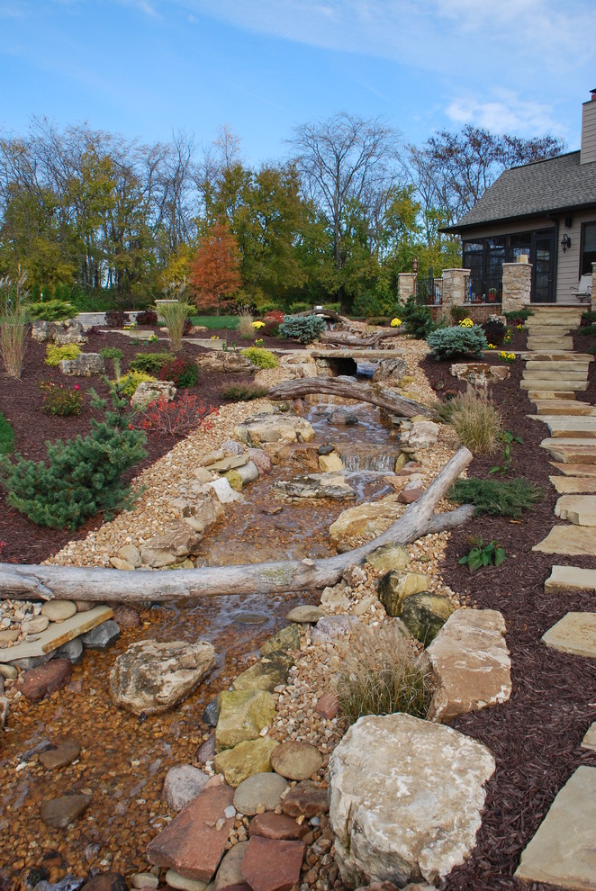 Modelo de jardín rural grande en otoño en patio trasero con fuente y adoquines de piedra natural