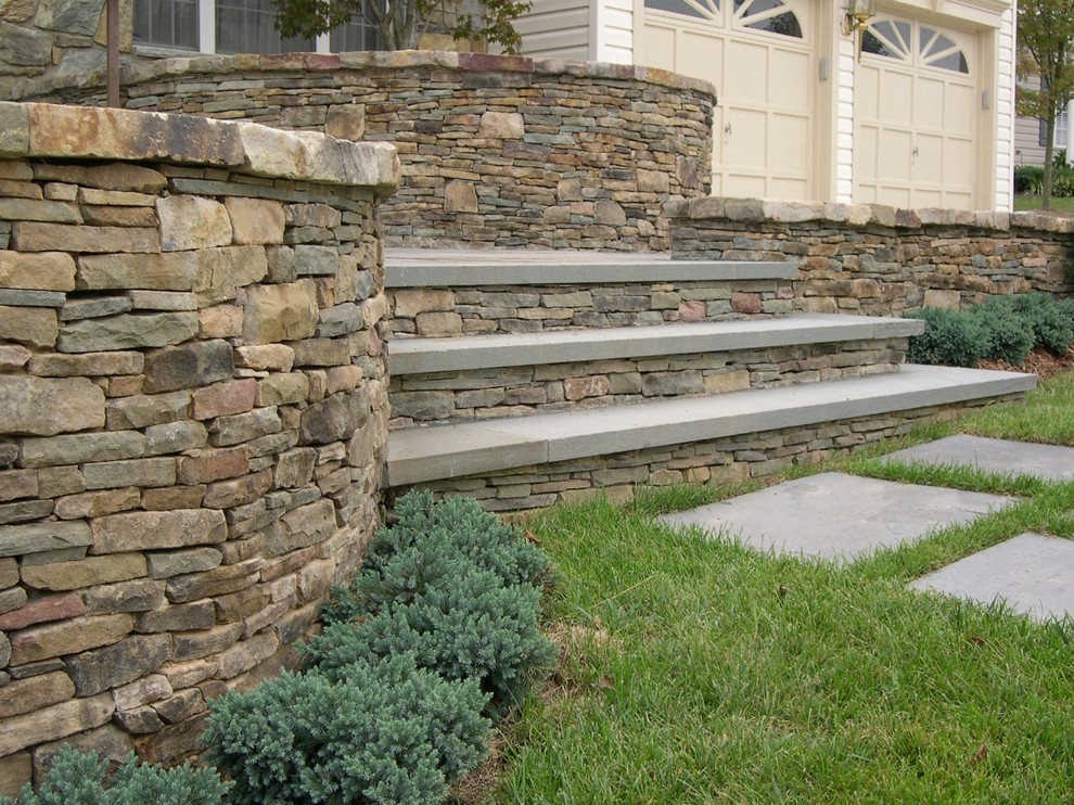 This is an example of a large contemporary full sun front yard stone retaining wall landscape in DC Metro.