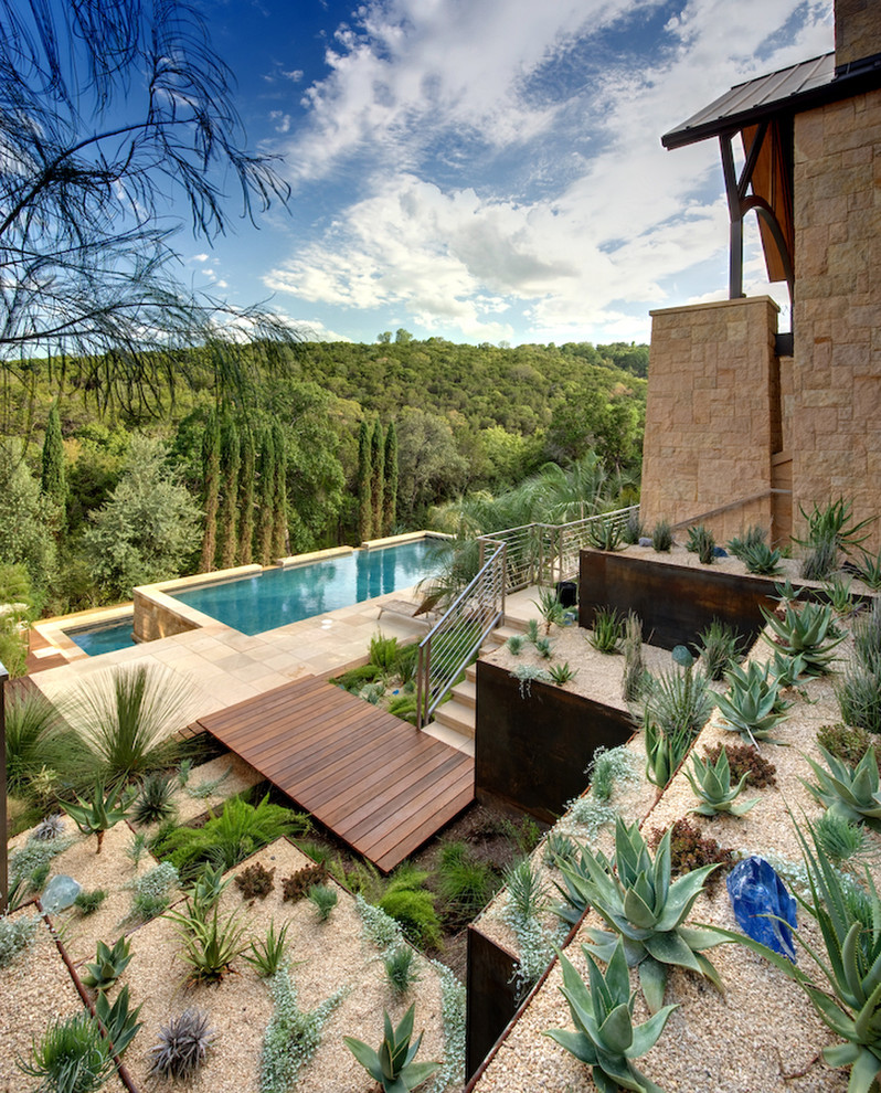 Пример оригинального дизайна: большой солнечный засухоустойчивый сад на склоне в стиле фьюжн с хорошей освещенностью, мощением тротуарной плиткой и пустынными растениями