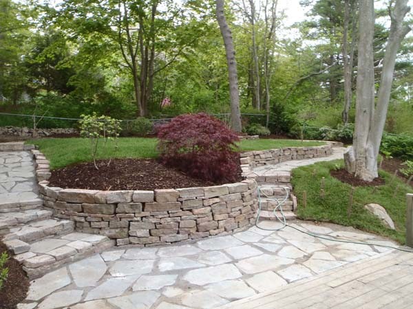 Idee per un grande giardino tradizionale in ombra dietro casa con un muro di contenimento e pavimentazioni in pietra naturale