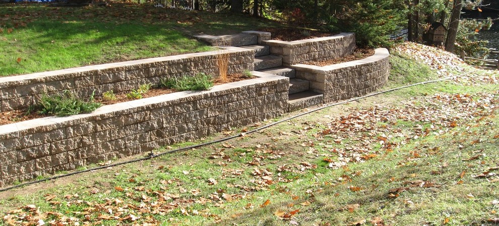 Design ideas for a medium sized traditional back partial sun garden in Other with a retaining wall and natural stone paving.