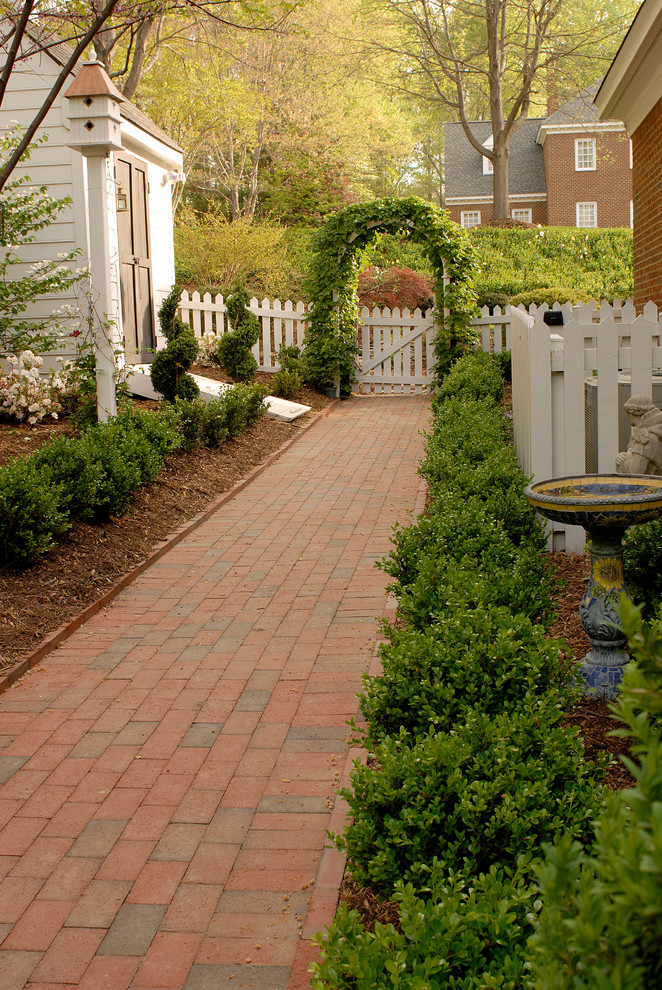 Photo of a mid-sized traditional partial sun side yard brick garden path in Other for spring.