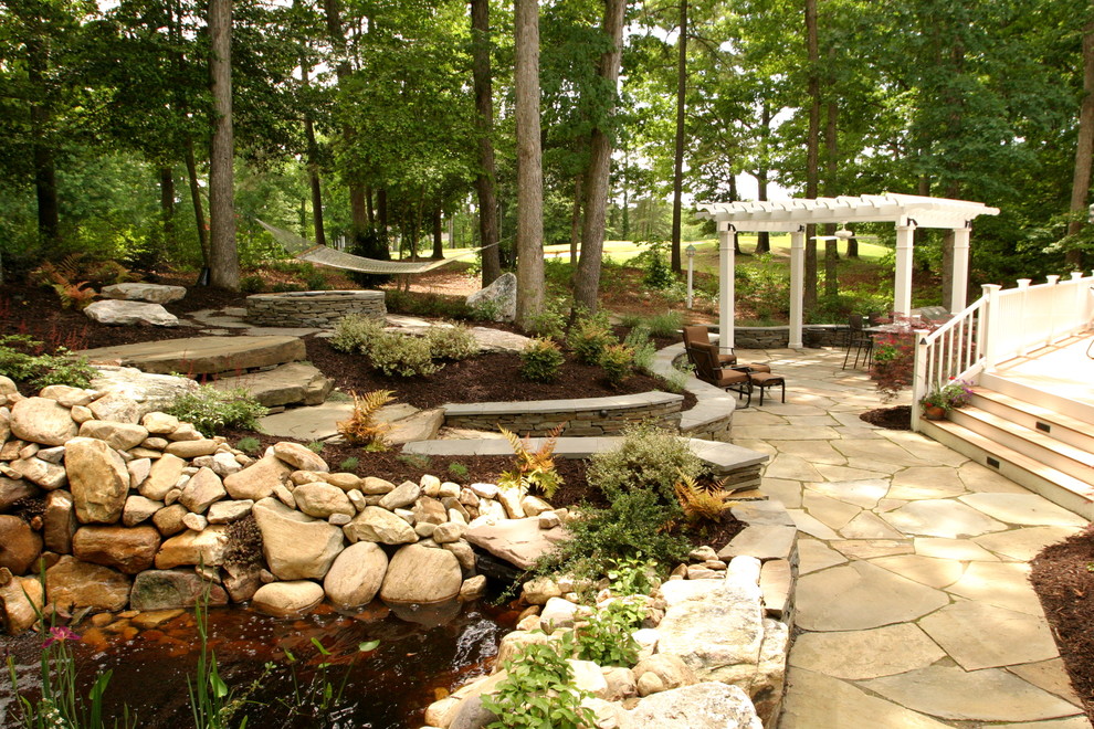 This is an example of a medium sized classic back fully shaded garden for summer in Other with a pond and natural stone paving.
