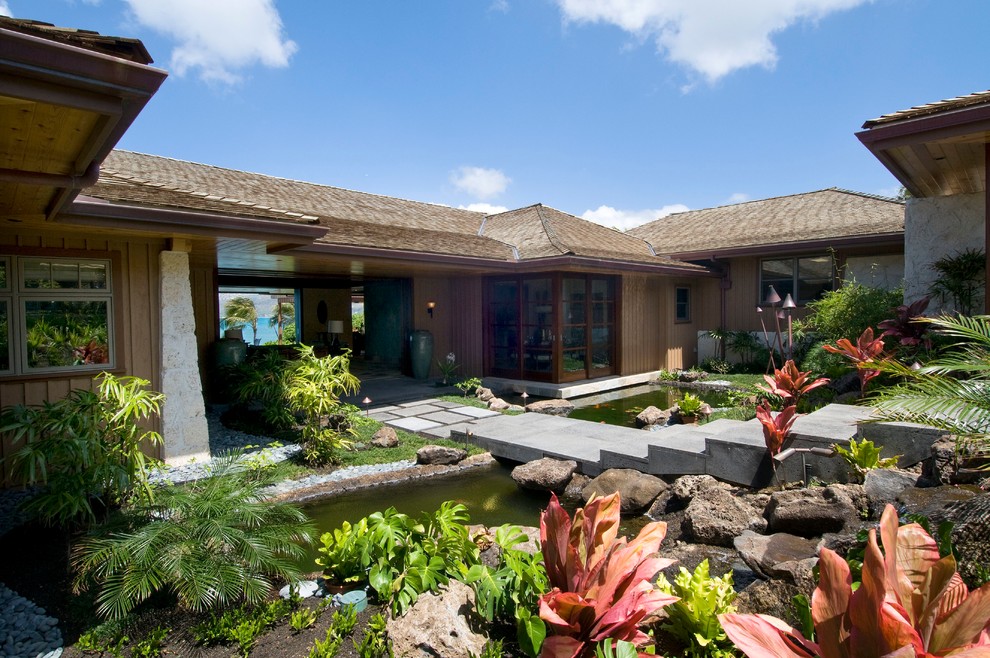 This is an example of a large world-inspired back full sun garden in Hawaii with a water feature.