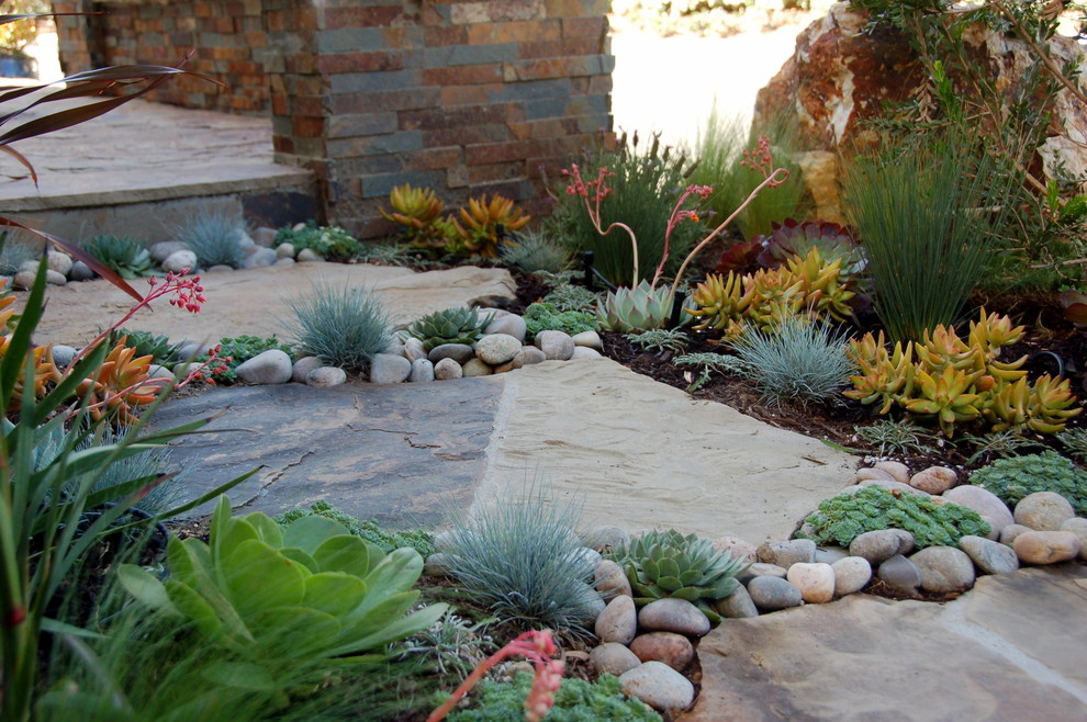 Foto de jardín actual en patio delantero con exposición total al sol y adoquines de piedra natural