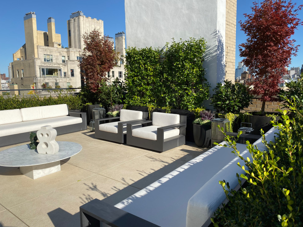 Photo of an expansive modern roof formal full sun garden in New York with a potted garden, natural stone paving and a metal fence.