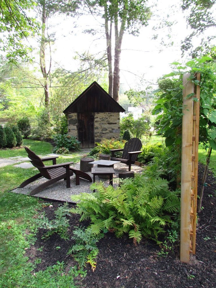 Small rustic back full sun garden for spring in Philadelphia with a fire feature and gravel.