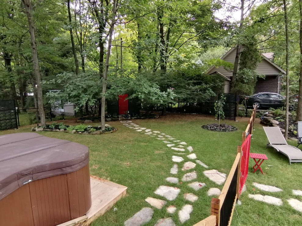 Inspiration pour un grand jardin arrière design l'été avec une exposition partiellement ombragée, des pavés en pierre naturelle et une clôture en métal.