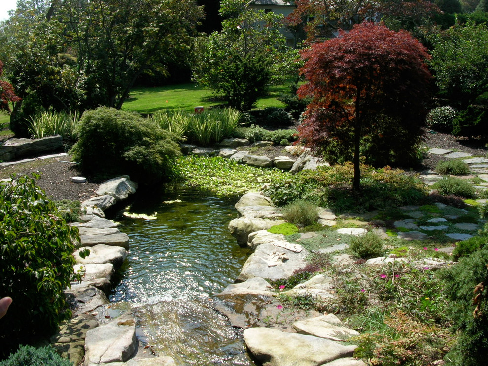 Exemple d'un jardin latéral chic de taille moyenne avec un point d'eau, une exposition ensoleillée et des pavés en pierre naturelle.
