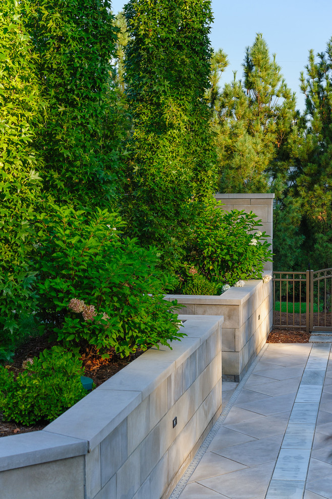 Immagine di un giardino formale design esposto in pieno sole di medie dimensioni e dietro casa in estate con un muro di contenimento e pavimentazioni in pietra naturale