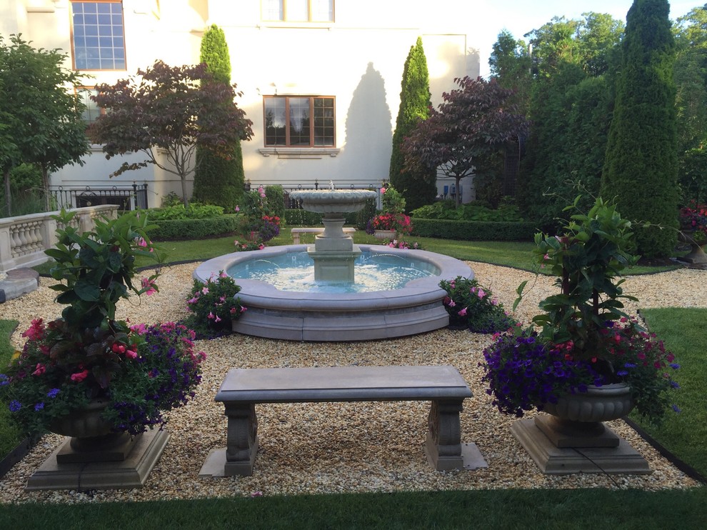 This is an example of an expansive mediterranean courtyard formal garden in New York with a water feature and gravel.