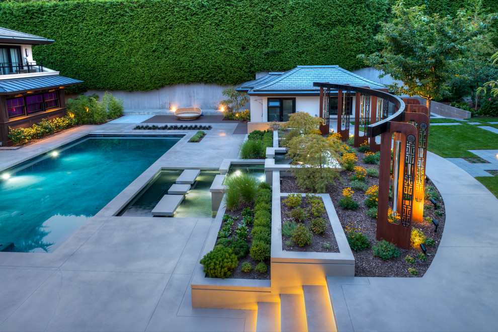 This is an example of a large world-inspired back formal full sun garden for summer in Vancouver with a water feature and natural stone paving.
