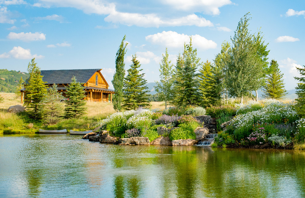 Photo of a large rustic back full sun garden in Denver with a pond.