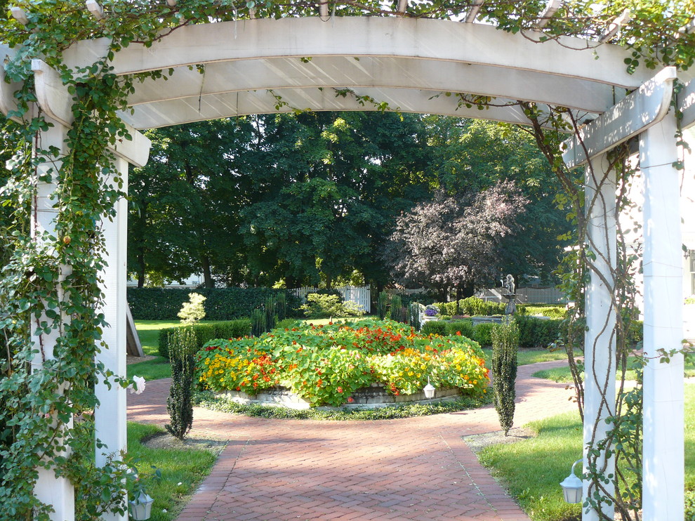 Imagen de jardín tradicional grande en patio trasero con jardín francés y adoquines de ladrillo