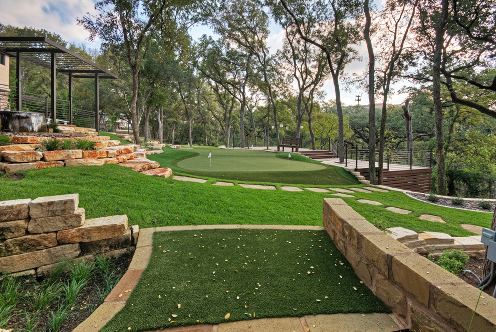 Large classic front formal fully shaded garden for spring in Austin with a retaining wall and natural stone paving.