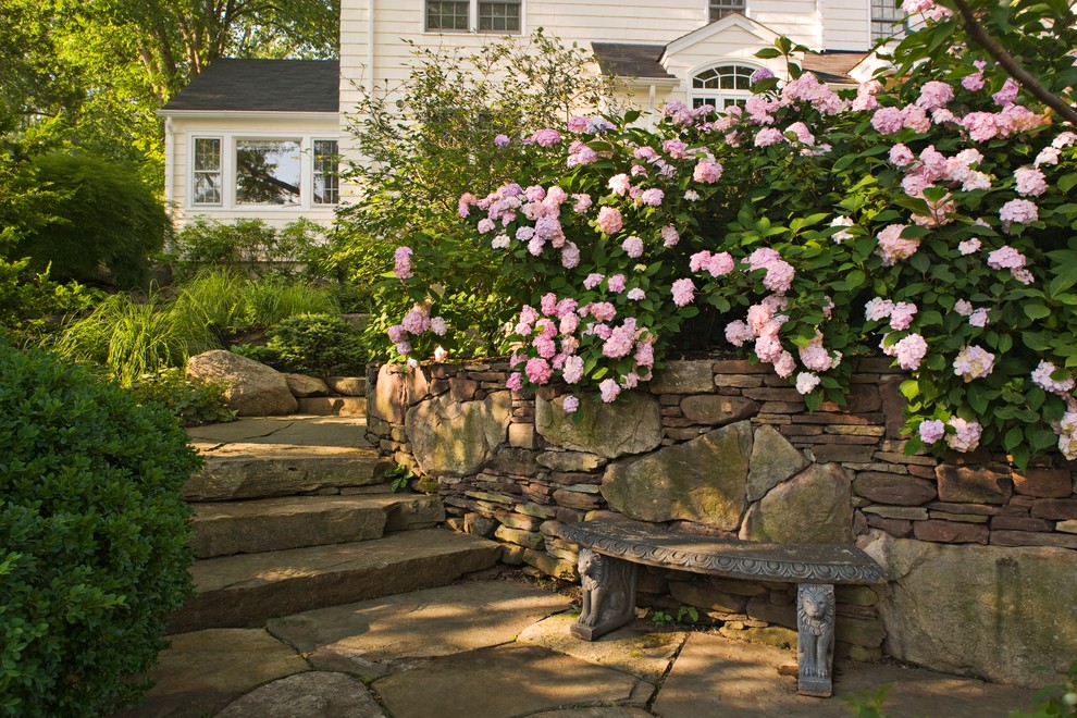 Imagen de jardín tradicional en verano en ladera con adoquines de piedra natural