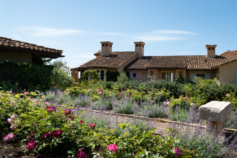 На фото: большой солнечный регулярный сад на заднем дворе в средиземноморском стиле с клумбами, хорошей освещенностью и покрытием из гравия с