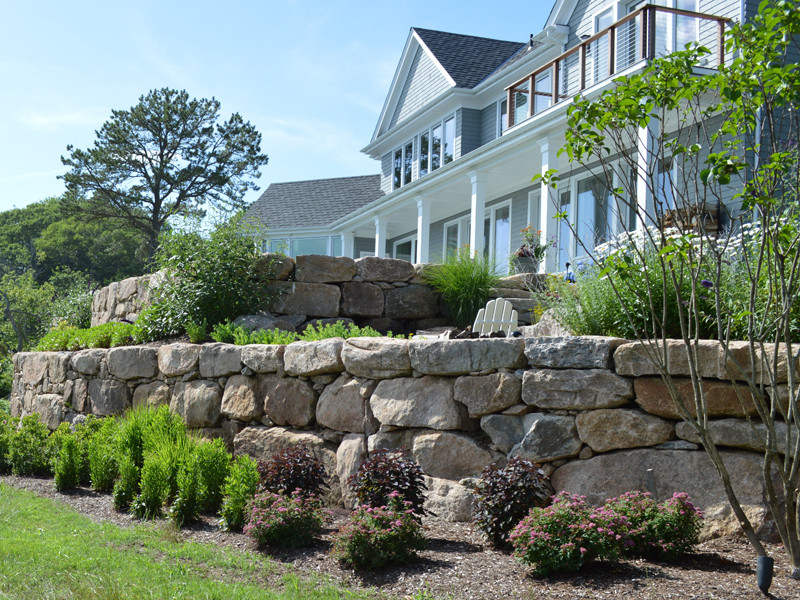 Idee per un giardino stile marinaro esposto in pieno sole dietro casa in estate con un muro di contenimento e pavimentazioni in pietra naturale