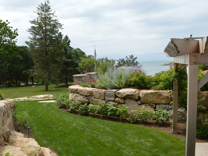 Пример оригинального дизайна: летний участок и сад на боковом дворе в морском стиле с подпорной стенкой, полуденной тенью и покрытием из каменной брусчатки