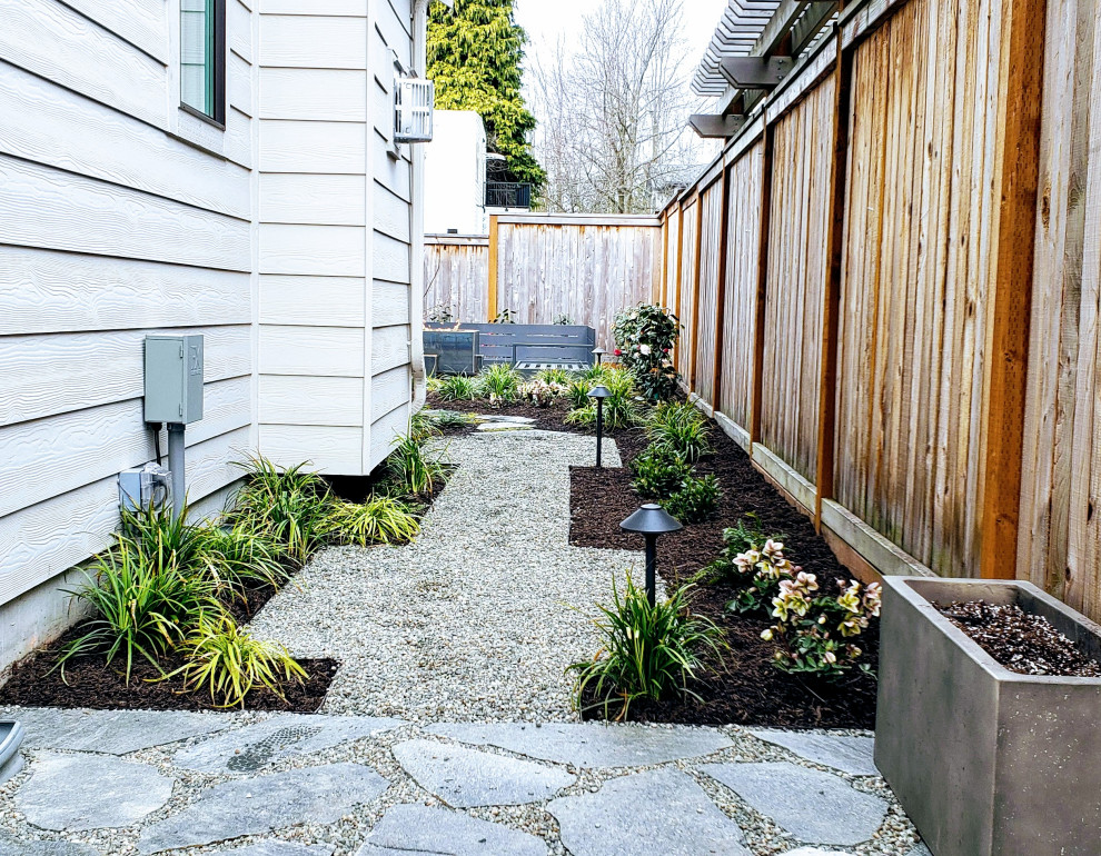 Photo of a small modern back xeriscape partial sun garden for summer in Seattle with a garden path and gravel.