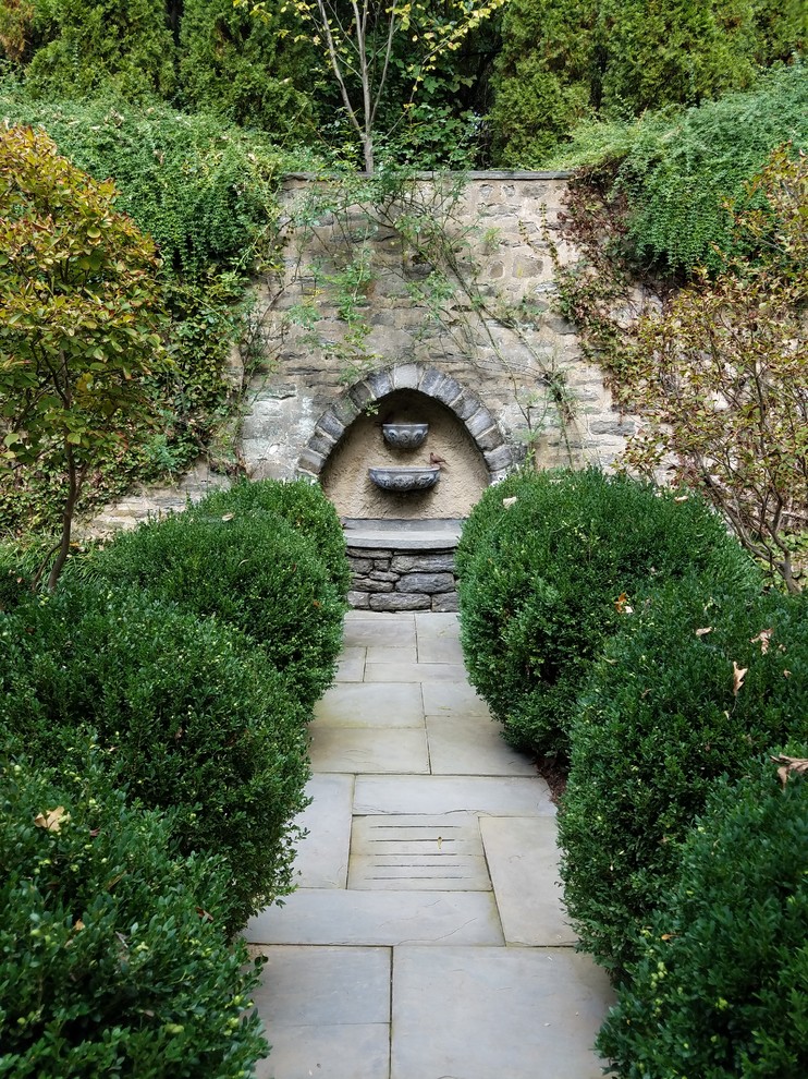 Diseño de jardín clásico pequeño en verano en patio con jardín francés, fuente, exposición parcial al sol y adoquines de piedra natural