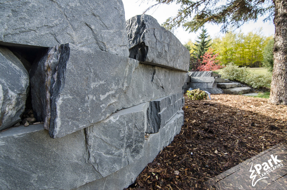 Inspiration for a large contemporary hillside stone landscaping in Calgary.