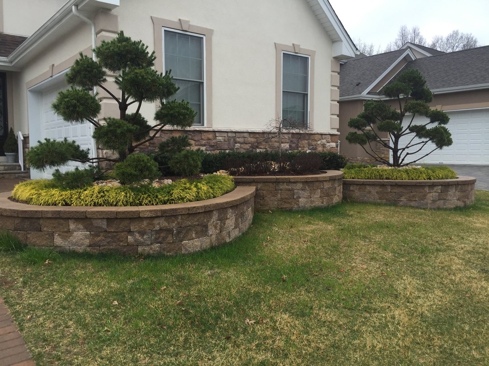 This is an example of a medium sized traditional front garden in New York with a retaining wall and concrete paving.