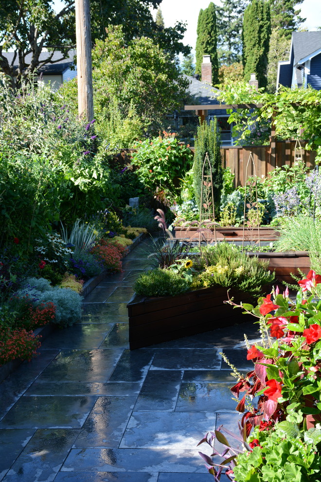 Bild på en mellanstor vintage bakgård i full sol, med en köksträdgård och naturstensplattor
