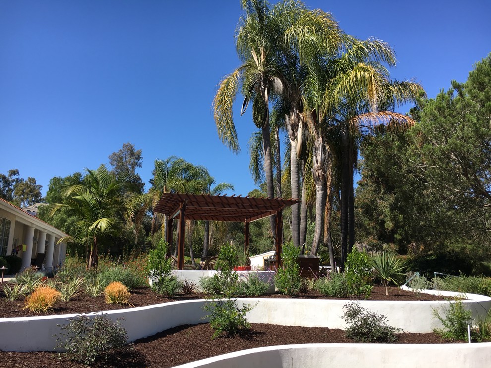 На фото: солнечный засухоустойчивый сад на заднем дворе в морском стиле с подпорной стенкой и хорошей освещенностью