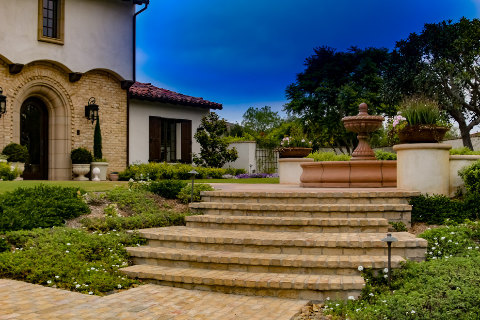 Esempio di un ampio giardino formale mediterraneo esposto in pieno sole dietro casa in primavera con un ingresso o sentiero e graniglia di granito