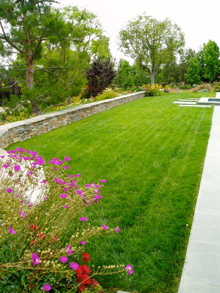 Idee per un grande giardino tradizionale esposto in pieno sole dietro casa con un muro di contenimento e pavimentazioni in pietra naturale