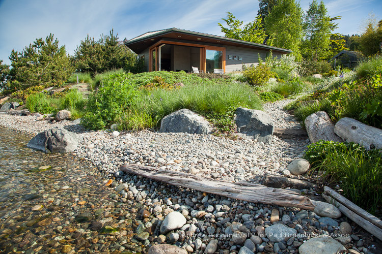 Modelo de jardín costero grande en verano en patio trasero con fuente, exposición total al sol y adoquines de piedra natural