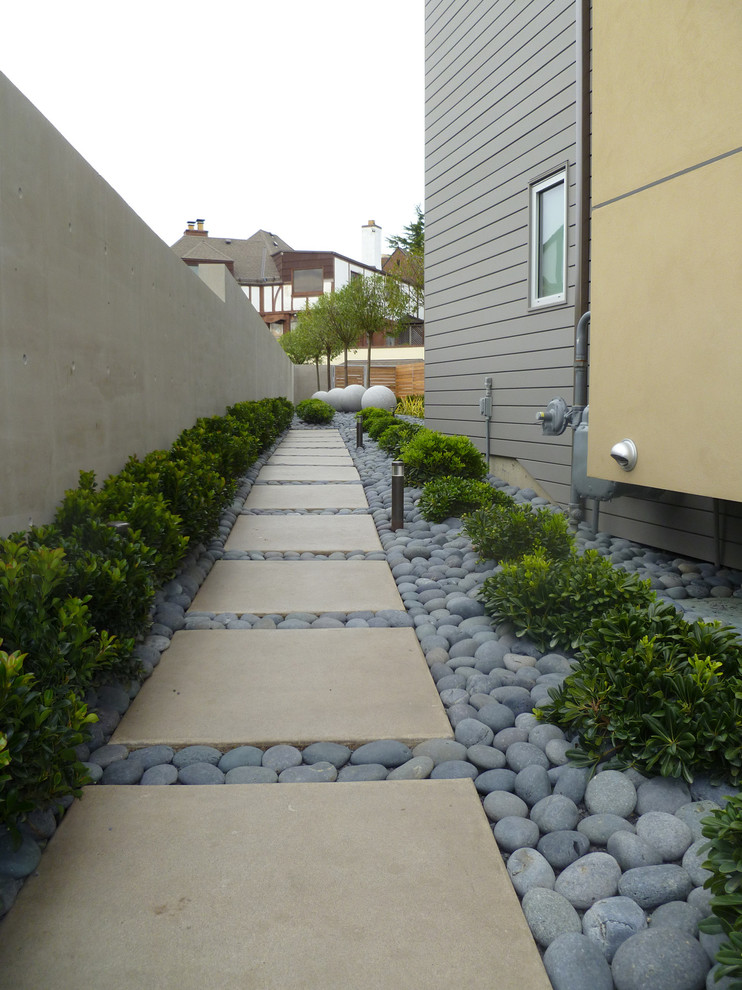 Exemple d'un jardin latéral tendance avec des galets de rivière.