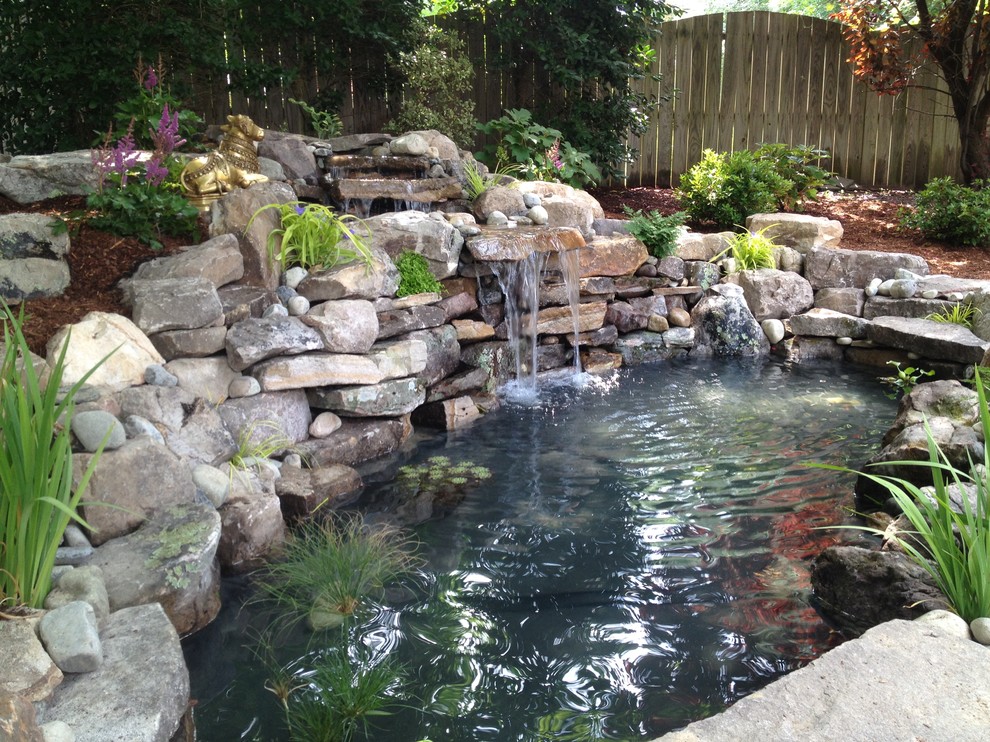 Medium sized classic back fully shaded garden for summer in Richmond with a pond and mulch.