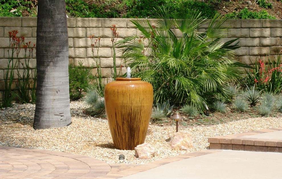 Ejemplo de jardín actual grande en patio trasero con exposición parcial al sol, adoquines de piedra natural, jardín francés y fuente