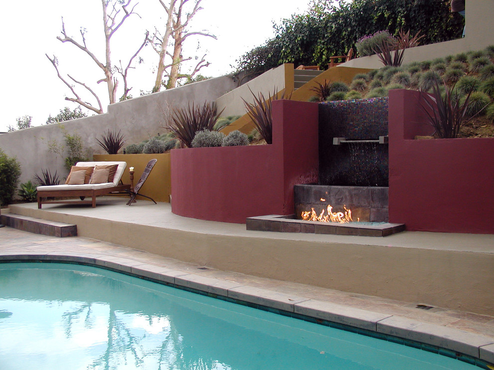 This is an example of a large contemporary full sun hillside stone landscaping in Los Angeles with a fire pit.