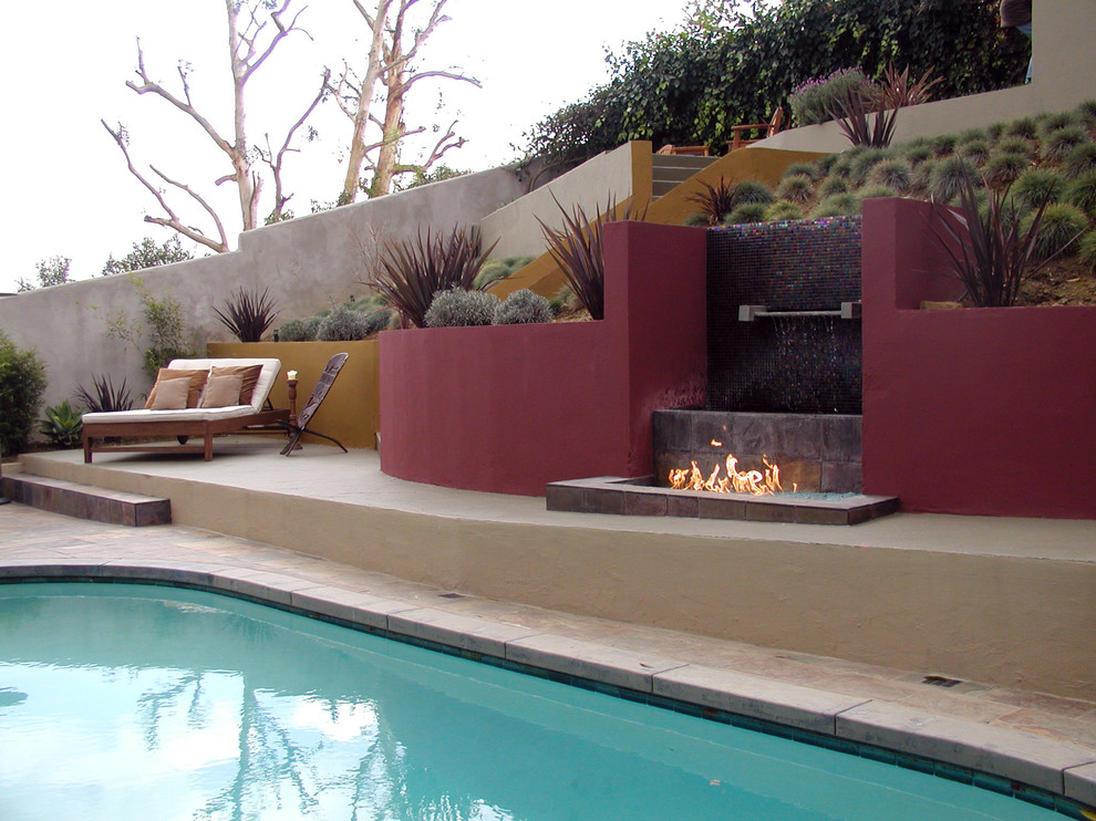 This is an example of a large contemporary full sun hillside stone landscaping in Los Angeles with a fire pit.