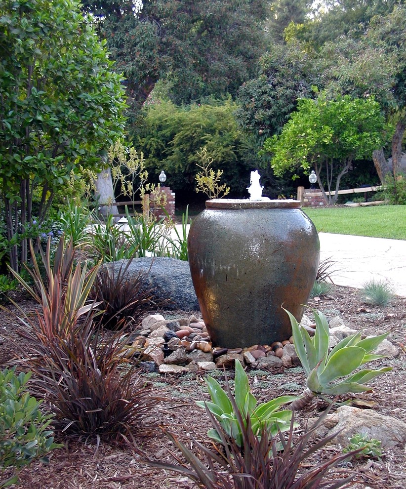 Ejemplo de jardín actual de tamaño medio en patio con jardín francés, fuente, exposición parcial al sol y adoquines de piedra natural