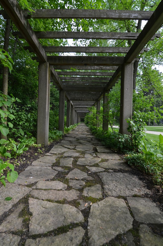 Diseño de jardín clásico grande en patio trasero con adoquines de piedra natural, jardín francés y pérgola