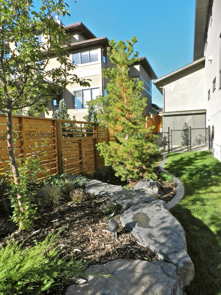 Geometrische, Mittelgroße Klassische Gartenmauer neben dem Haus mit direkter Sonneneinstrahlung und Mulch in Calgary