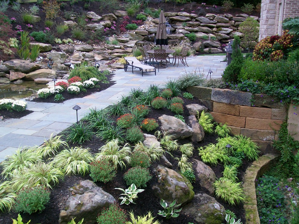 Cette photo montre un jardin tendance avec un mur de soutènement et des pavés en pierre naturelle.